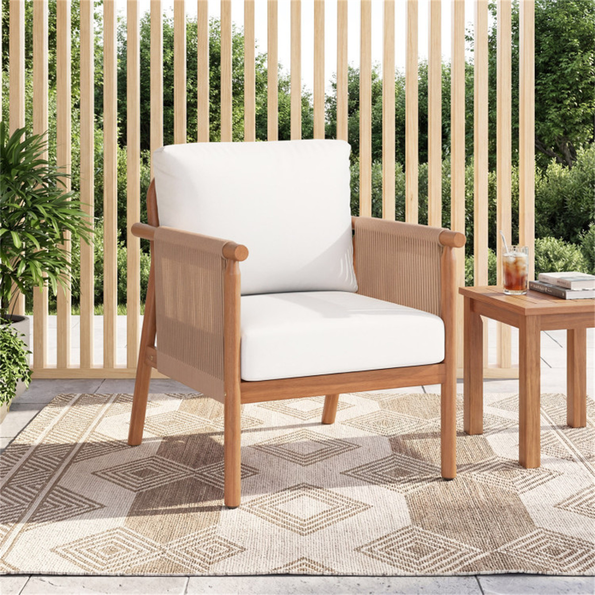 Wooden chair with white cushions on a patio with a small table and plants.