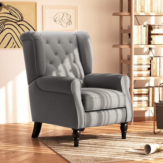 Gray armchair in a room with a bookshelf and decorative items.