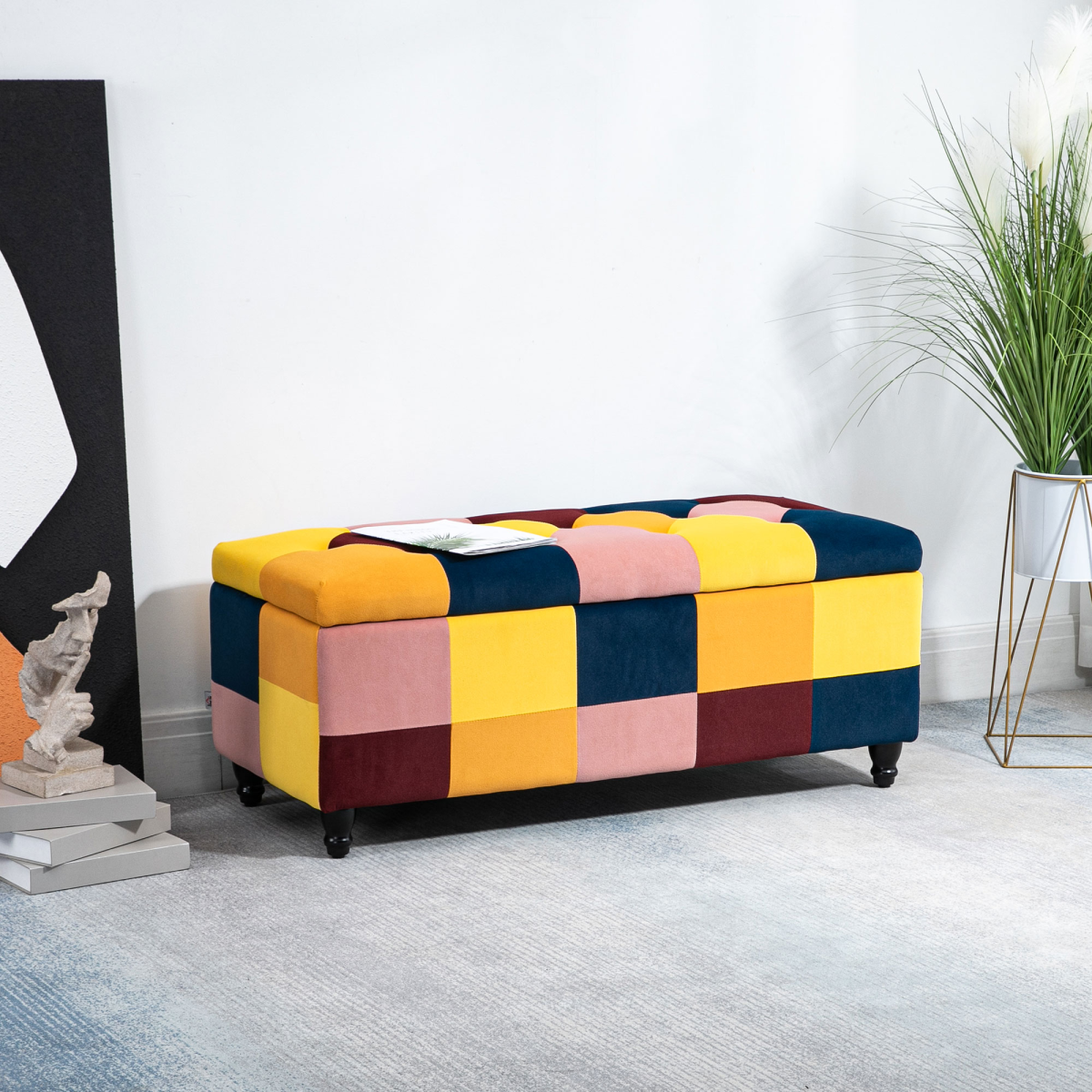 Multicolored checkered ottoman in a room with a plant and abstract art.