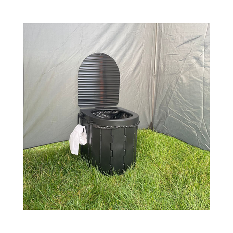 Black portable toilet on grass with a gray tent in the background