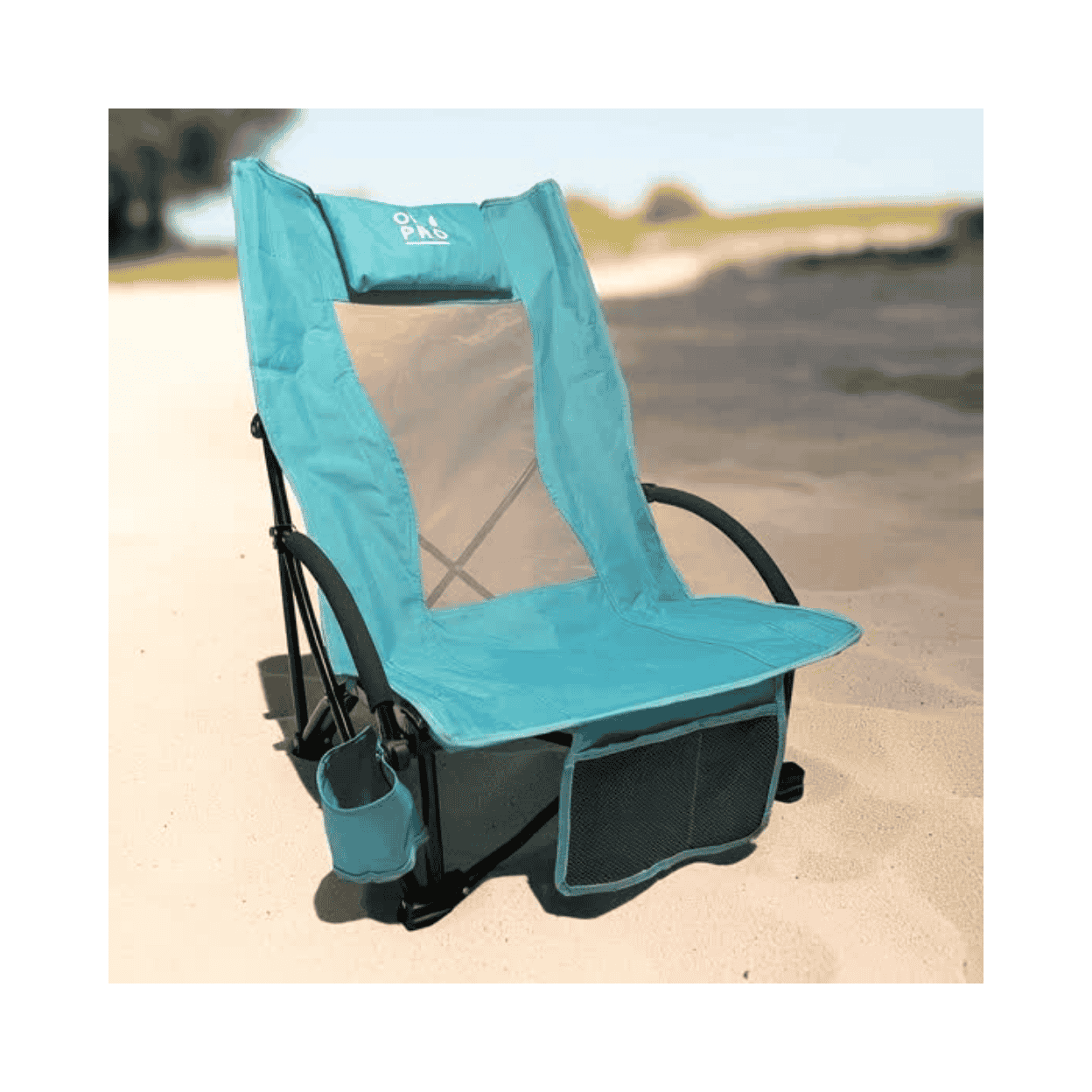 A teal and black beach chair with a mesh backrest, side cup holder, and front storage pocket, photographed outdoors on sand with a blurred beach background.