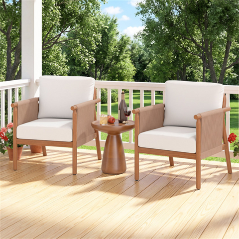 Two wooden chairs with white cushions on a wooden deck with a small table, surrounded by greenery.