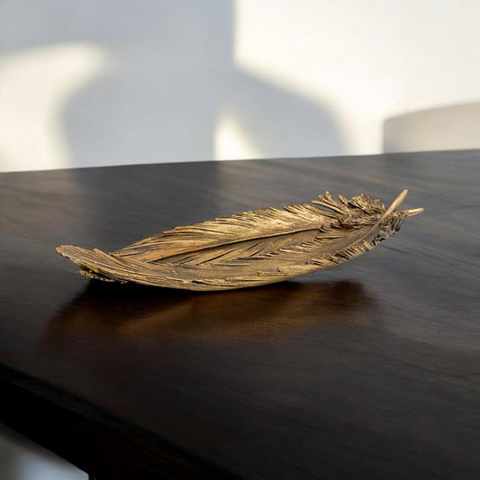 Decorative feather sculpture on a dark surface with a blurred background