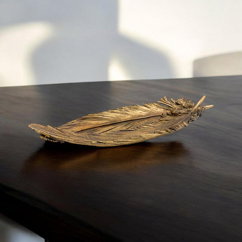 Decorative feather sculpture on a dark surface with a blurred background