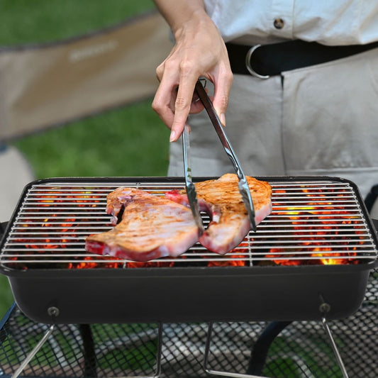 Person grilling fish on a portable barbecue grill outdoors.