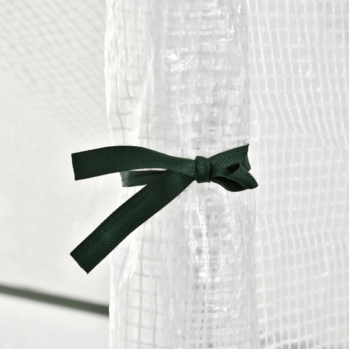 White textured fabric with a green ribbon tied in a bow on a white background